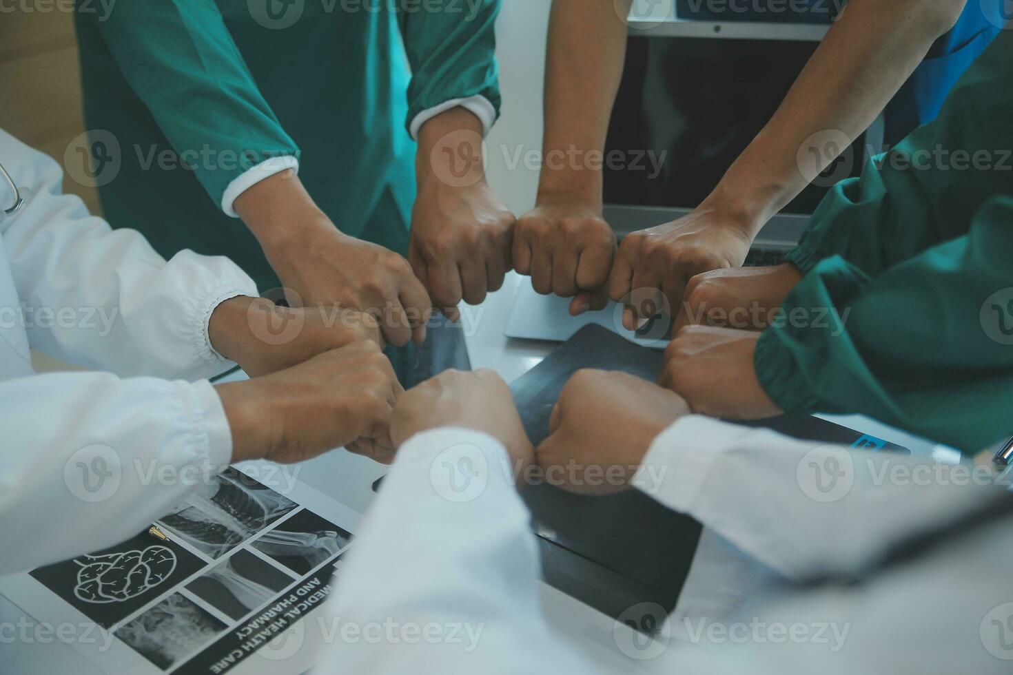 Mature doctors and young nurses stacking hands together at hospital. Close up hands of medical team stacking hands. Group of successful medical doctors and nurses stack of hands. photo