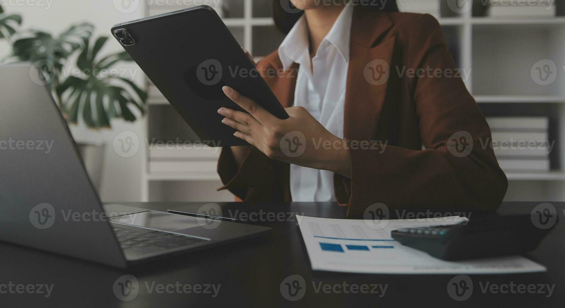 Asian Business woman using calculator and laptop for doing math finance on an office desk, tax, report, accounting, statistics, and analytical research concept photo