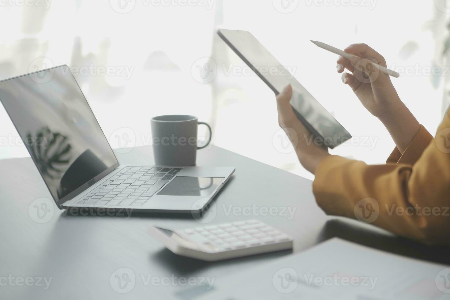 Asian Business woman using calculator and laptop for doing math finance on an office desk, tax, report, accounting, statistics, and analytical research concept photo