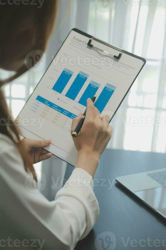 Portrait of Young Asian woman hand freelancer is working her job on computer tablet in modern office. Doing accounting analysis report real estate investment data, Financial and tax systems concept. photo