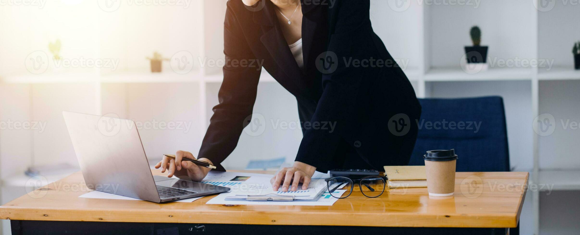 Asian Business woman using calculator and laptop for doing math finance on an office desk, tax, report, accounting, statistics, and analytical research concept photo