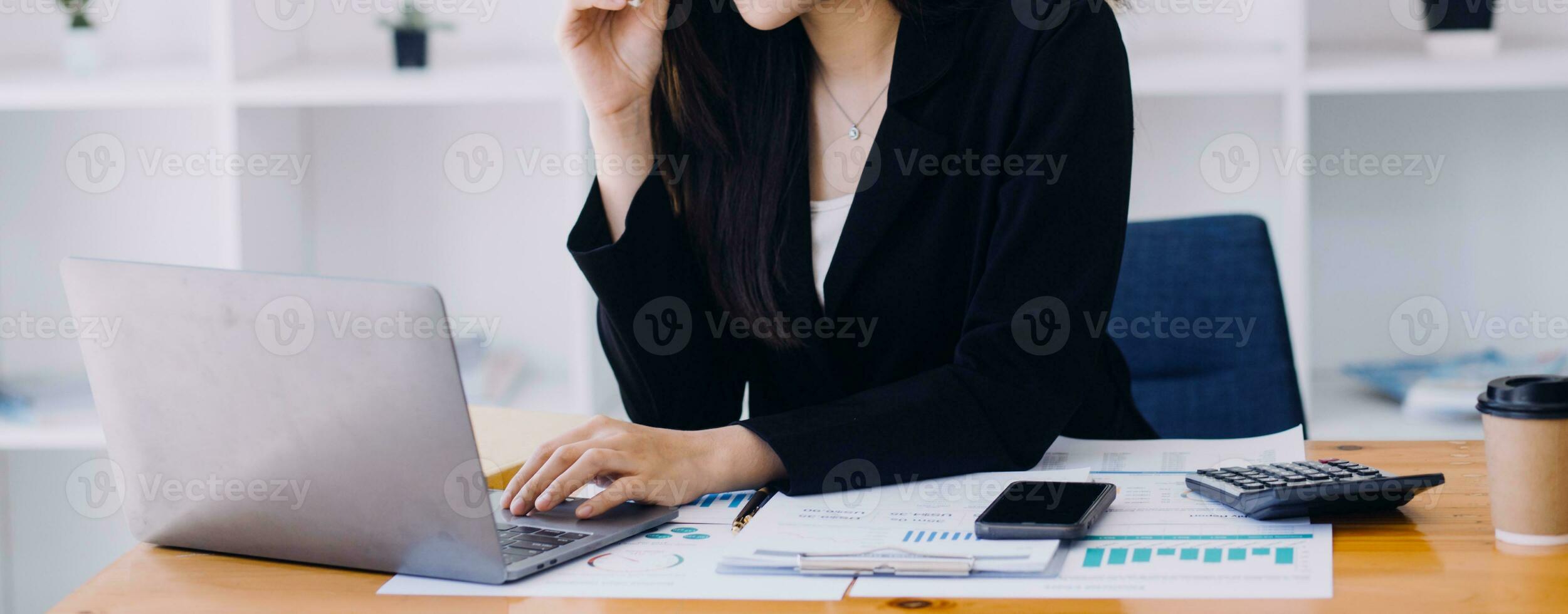 Asian Business woman using calculator and laptop for doing math finance on an office desk, tax, report, accounting, statistics, and analytical research concept photo