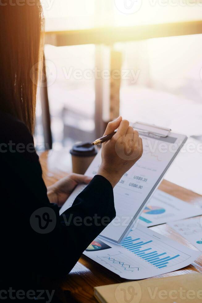 Asian Business woman using calculator and laptop for doing math finance on an office desk, tax, report, accounting, statistics, and analytical research concept photo