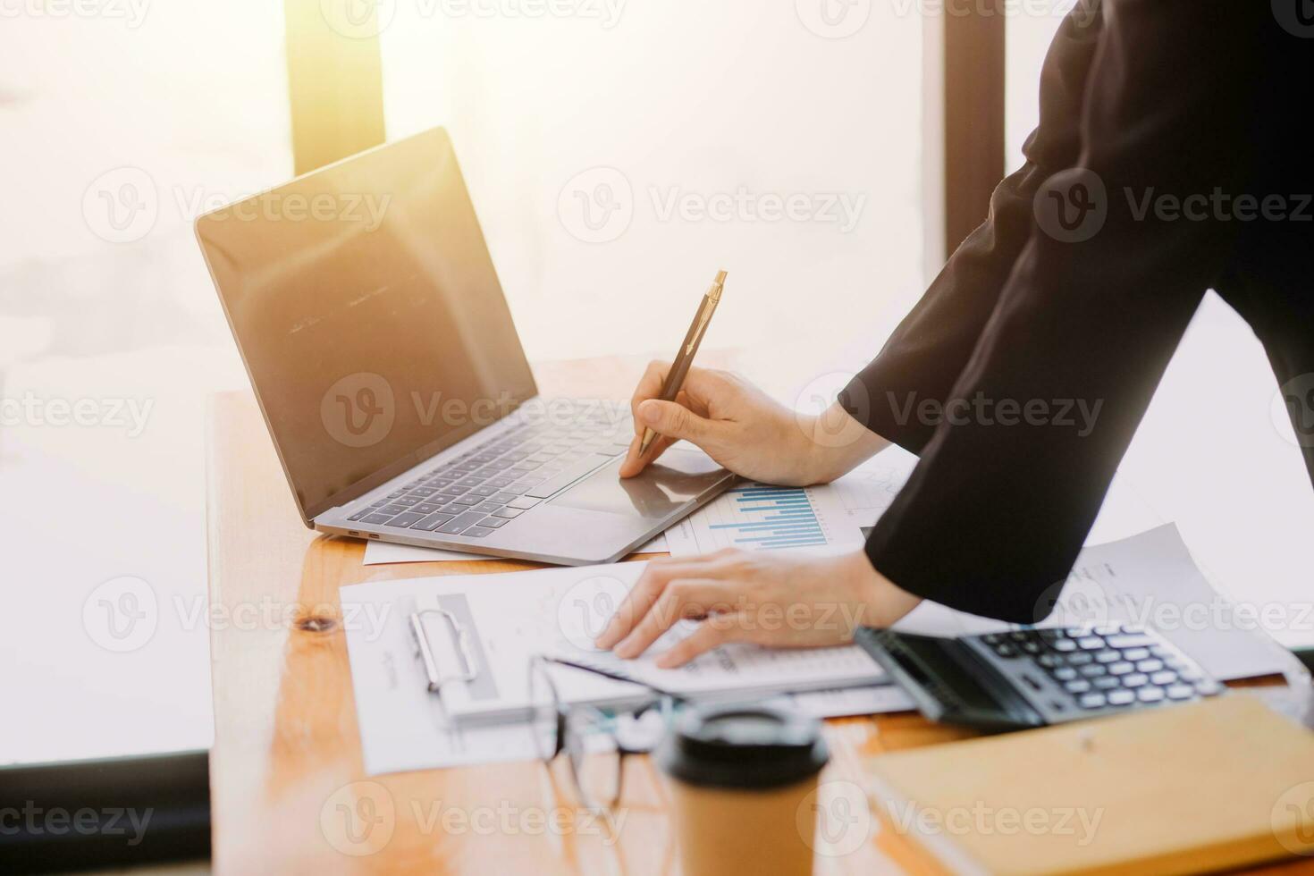 Asian Business woman using calculator and laptop for doing math finance on an office desk, tax, report, accounting, statistics, and analytical research concept photo