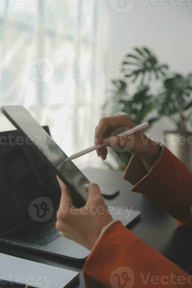 Portrait of Young Asian woman hand freelancer is working her job on computer tablet in modern office. Doing accounting analysis report real estate investment data, Financial and tax systems concept. photo