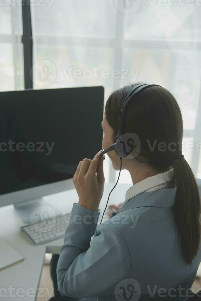 Beautiful female call center operator working on computer in office photo