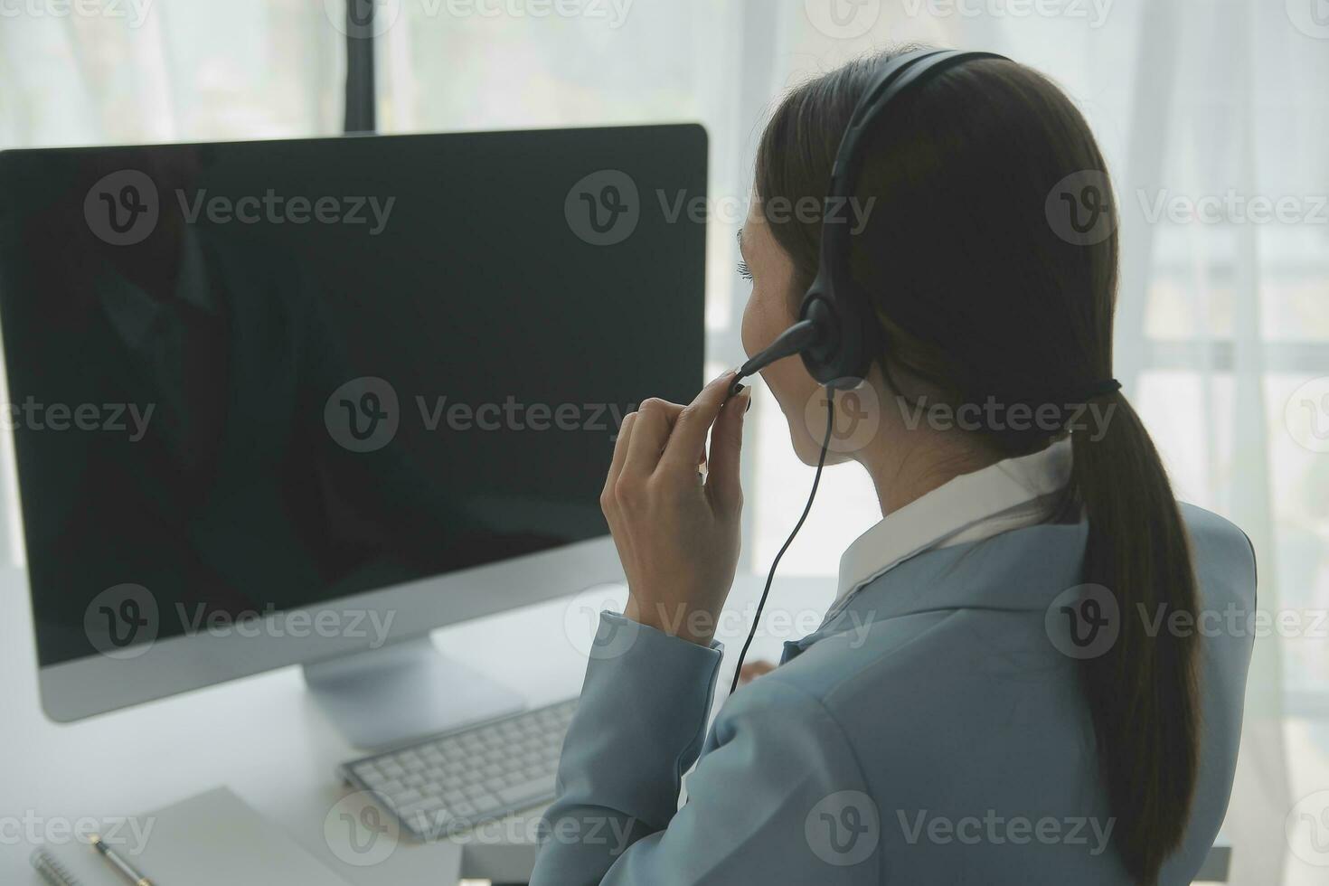 Beautiful female call center operator working on computer in office photo