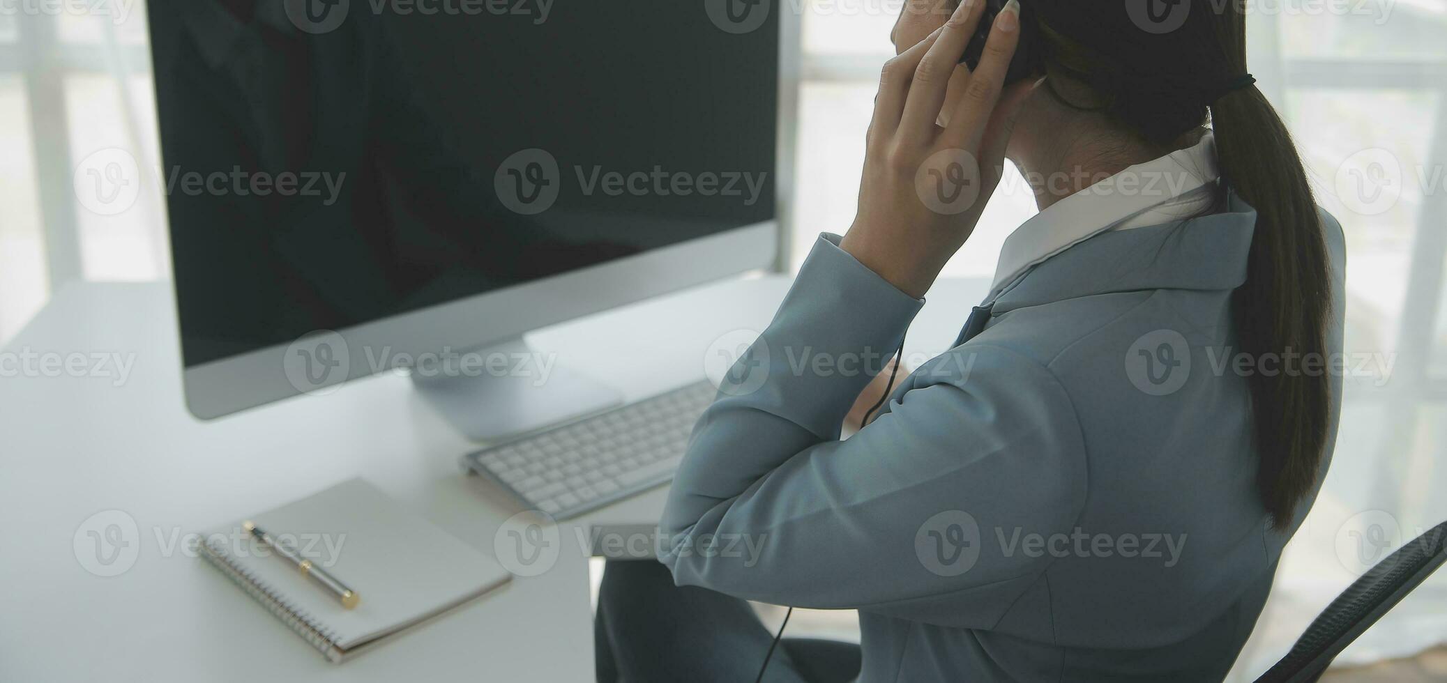 Beautiful female call center operator working on computer in office photo