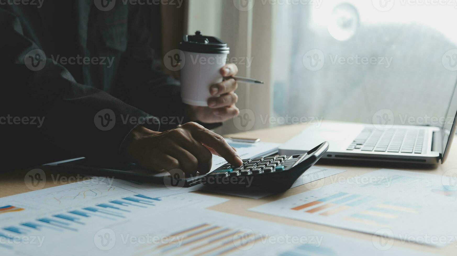 Close up businessman hand using calculator and working with laptop calculate about finance accounting at coffeeshop outdor.finance accounting concept photo