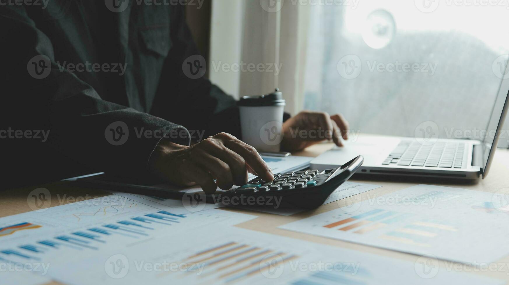 Close up businessman hand using calculator and working with laptop calculate about finance accounting at coffeeshop outdor.finance accounting concept photo