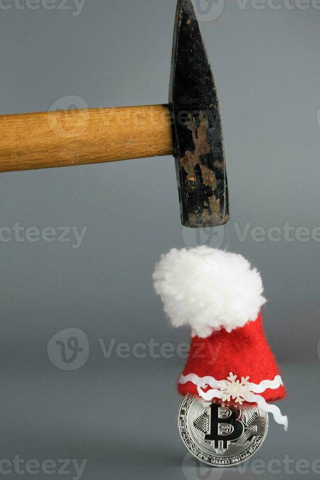 bitcoin en un Papa Noel claus sombrero y un martillo en un gris superficie. foto