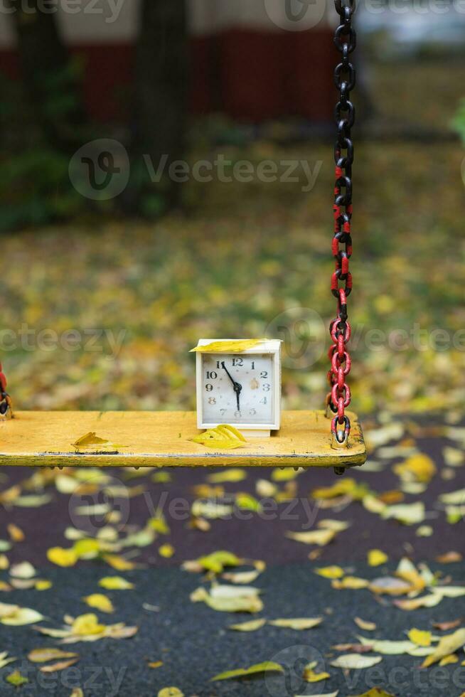 Old square alarm clock on a swing. photo