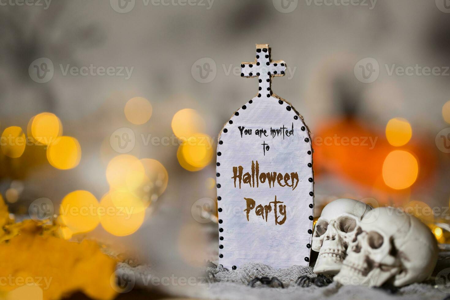 You are invited to Halloween party. Grave and two skulls. Closeup photo