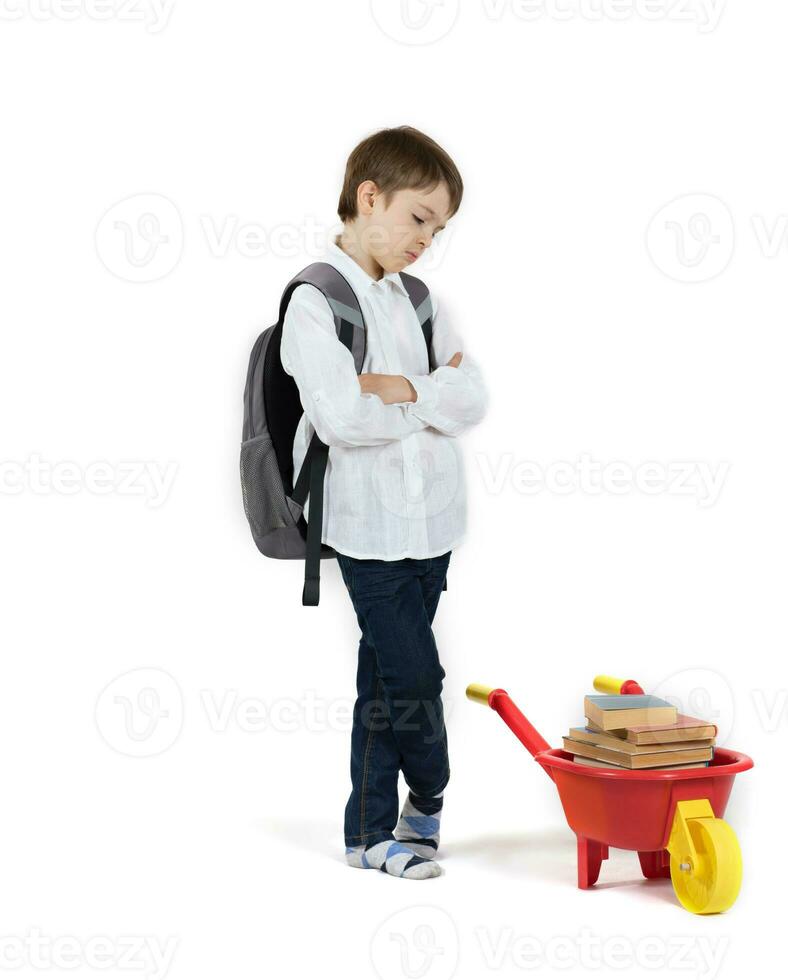 Schoolboy pushes plastic wheelbarrow full of books. Free space for a text. photo