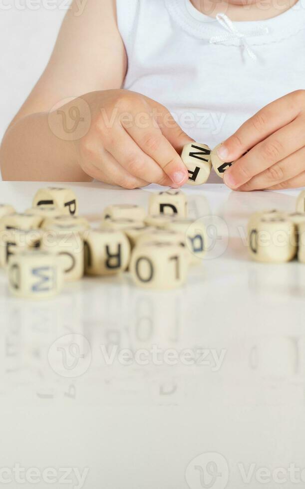 Small girl composes words from letters. Closeup photo