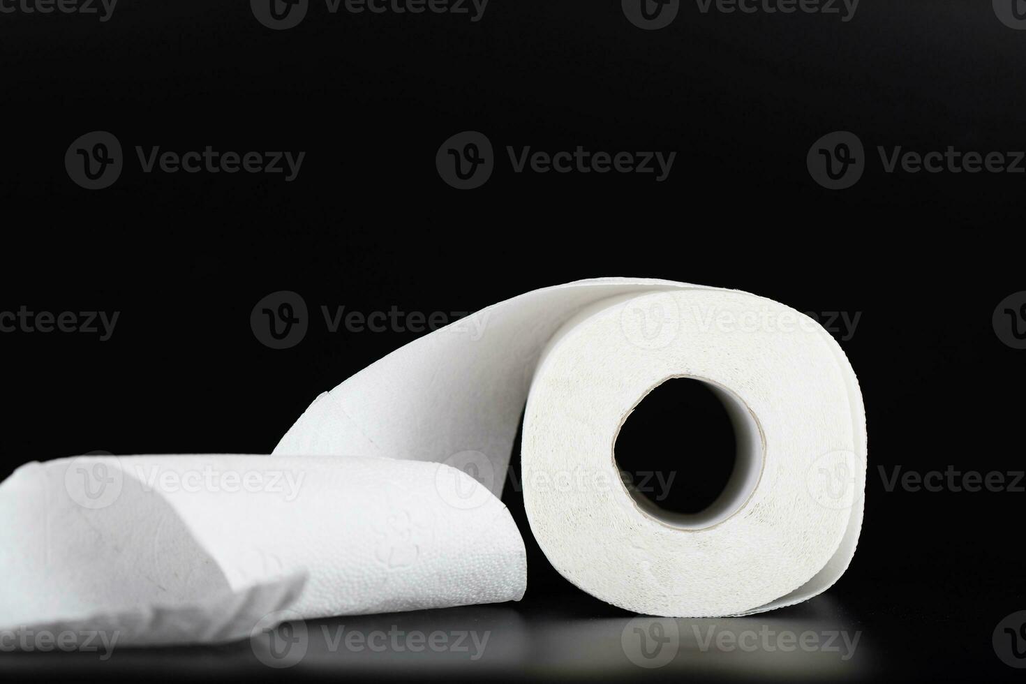 Roll of toilet paper on a black surface. photo