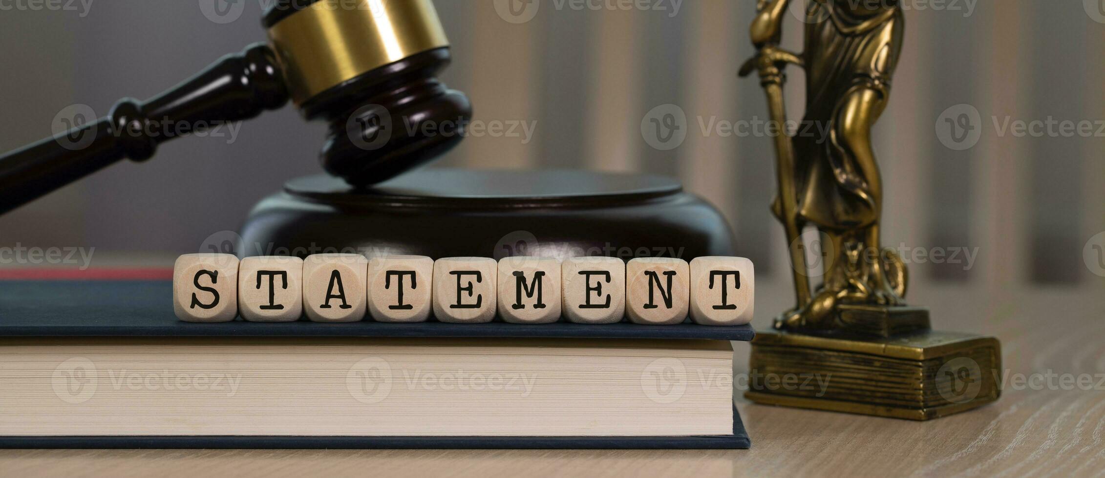 Word STATEMENT composed of wooden dices. Wooden gavel and statue of Themis in the background. photo