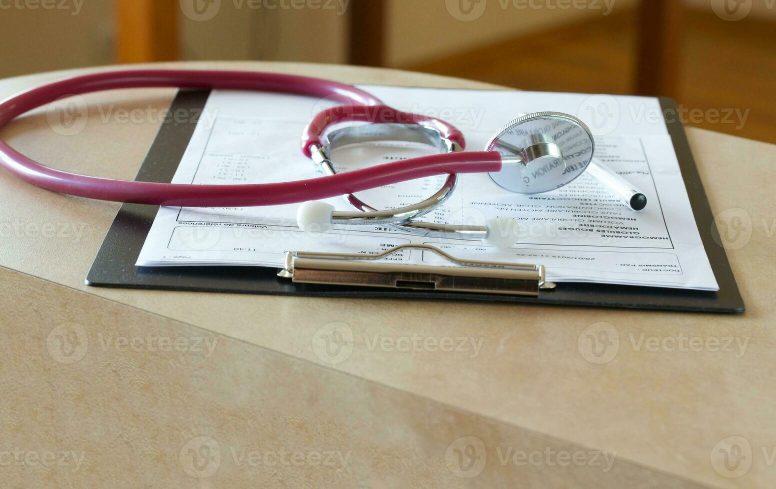 Stethoscope on a results of blood analysis in French a doctors table. Closeup photo