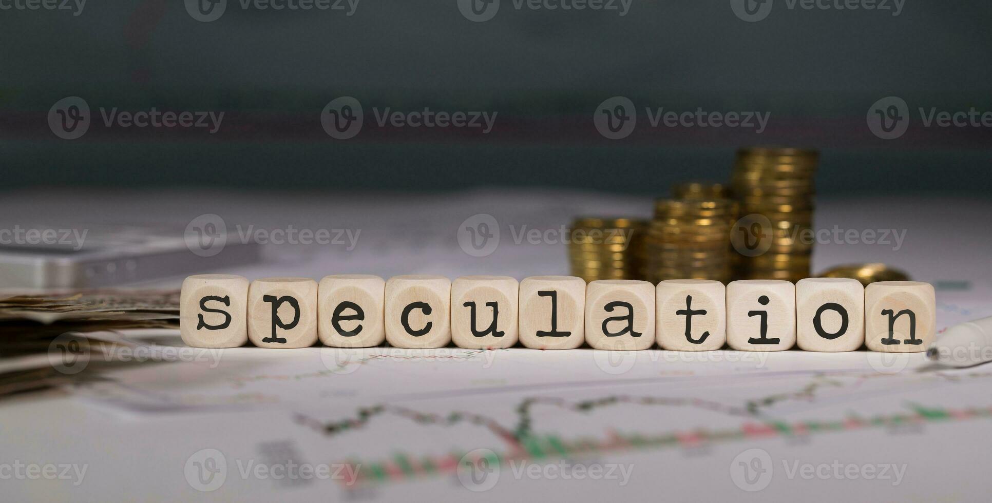 Word SPECULATION composed of wooden letter. Stacks of coins in the