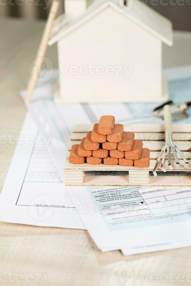 Red bricks for construction, mini rakes and sweeper on a small wooden pallet. photo