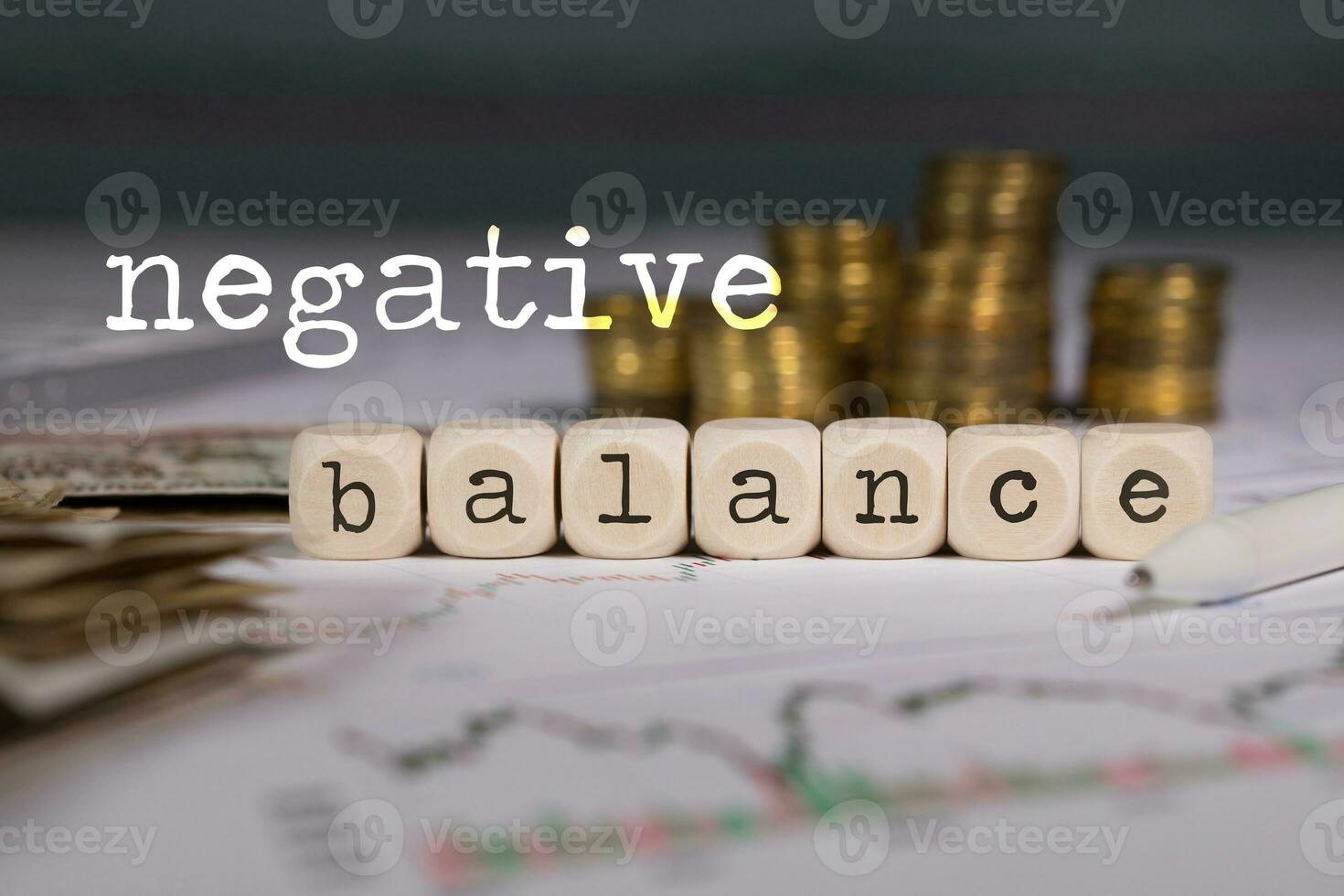 Term NEGATIVE BALANCE composed of wooden letters. Stacks of coins in the background. photo