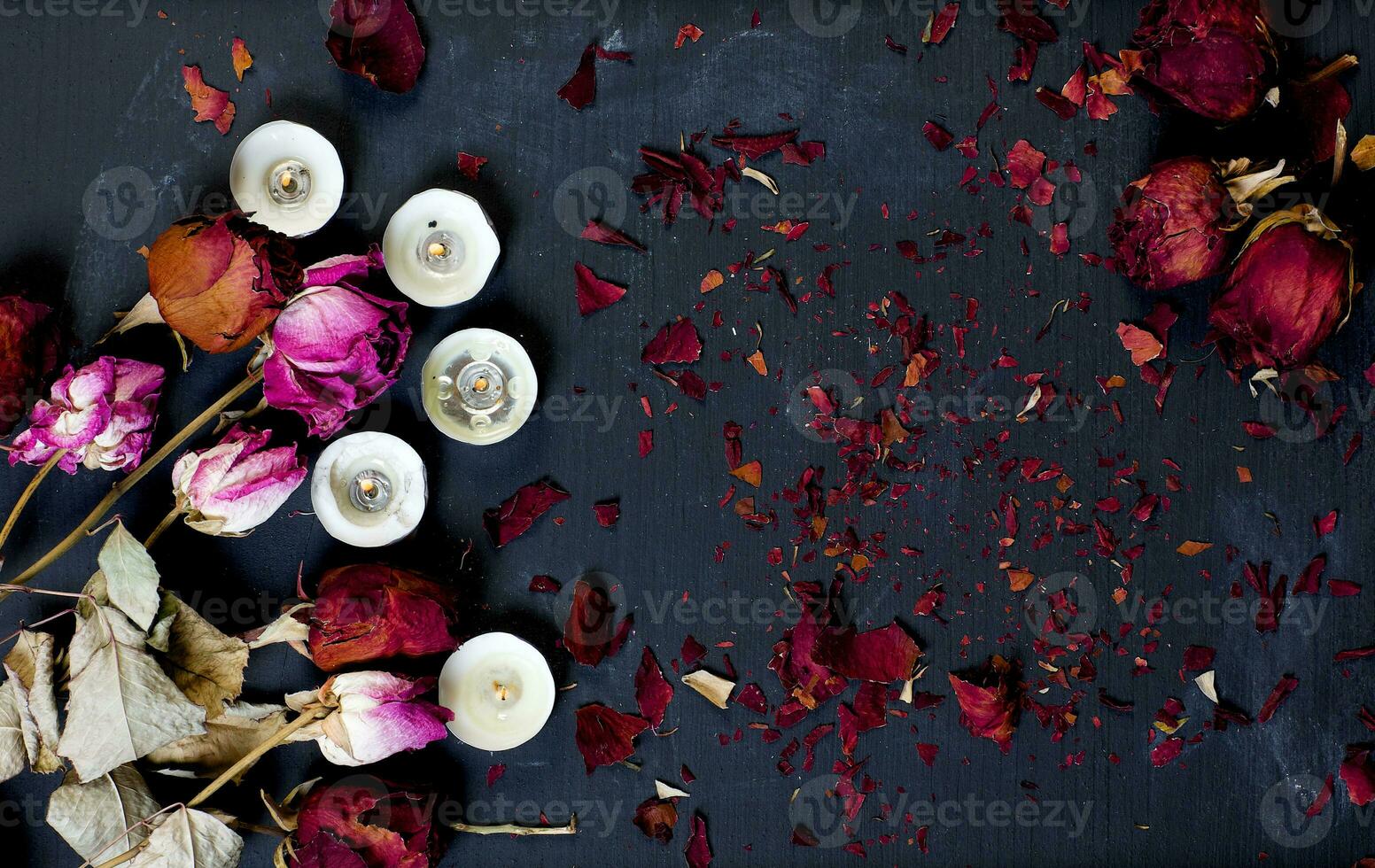 Dried roses and burning candles on a black chalk boar. Background photo