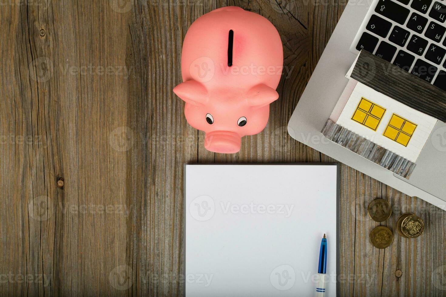 Blank sheet of paper and pink piggy bank close to the laptop. photo
