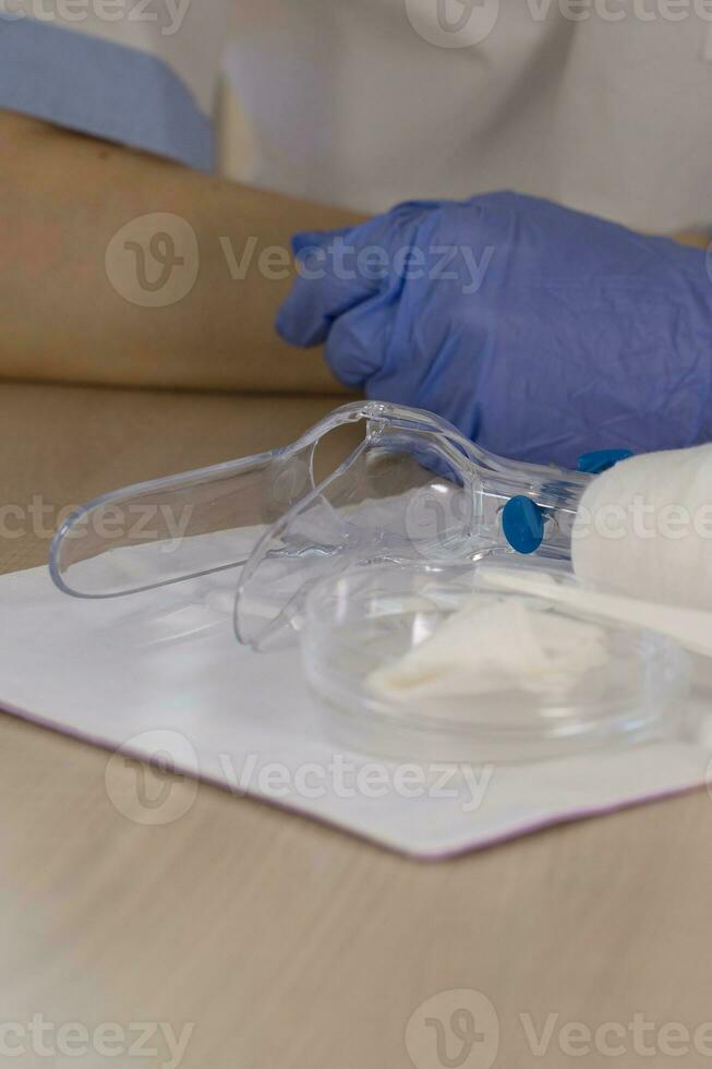 Plastic vaginal speculum and gynecologist in sterile gloves in the background. photo