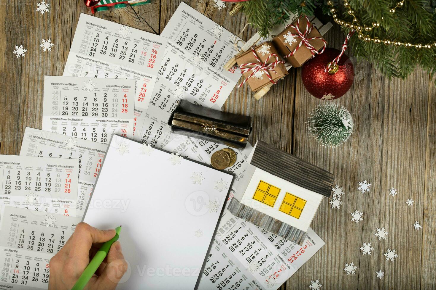 Blank sheet of paper and small paper house with coins on the New Year's background. photo