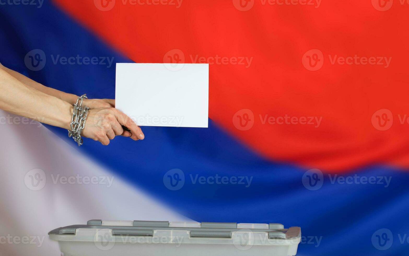 Female hands fastened by metal chain cast ballot paper in the ballot box. photo