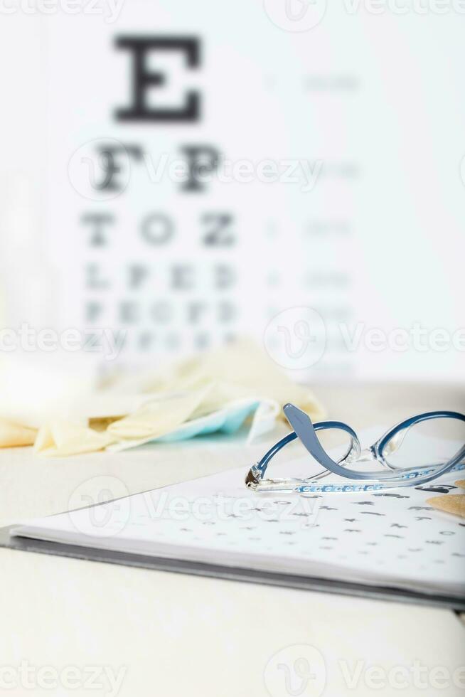 Eyeglasses for children on a eye chart close to eye pads. photo