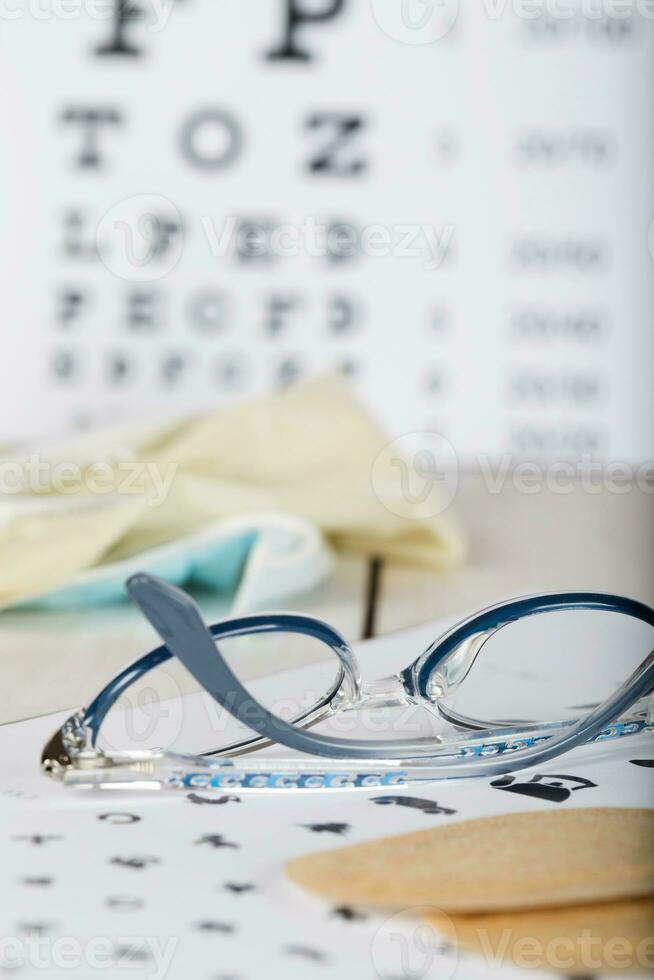 Eyeglasses for children on a eye chart close to eye pads. photo