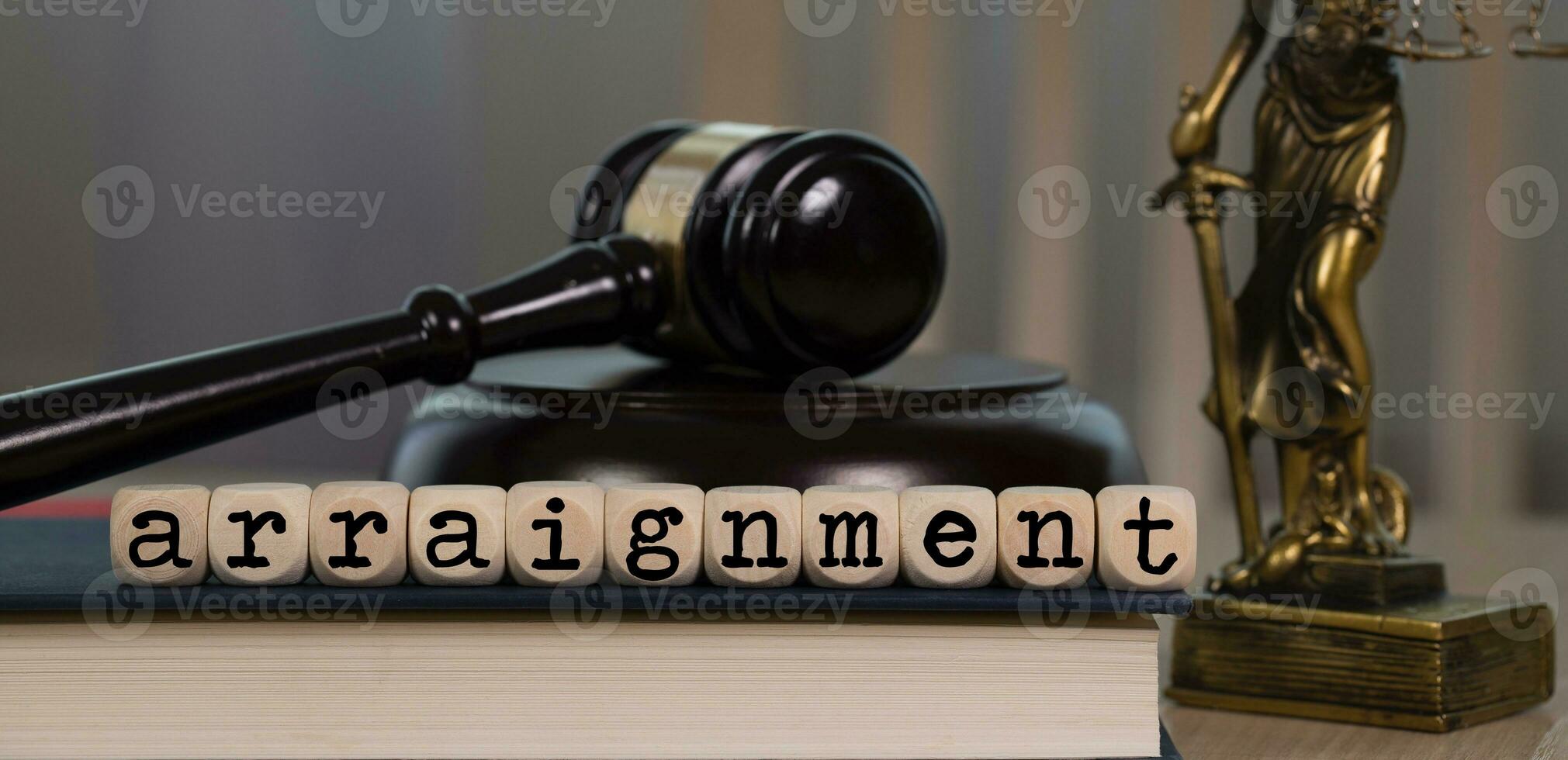 Word ARRAIGNMENT composed of wooden dices. Wooden gavel and statue of Themis in the background. photo
