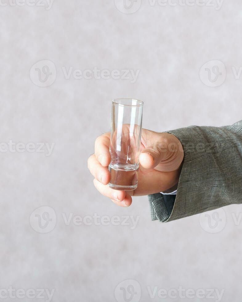 A small glass in the hand of a man photo