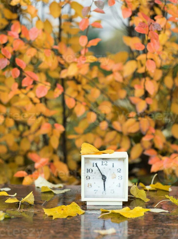 Old square alarm clock on a marble stone covered by rain. photo