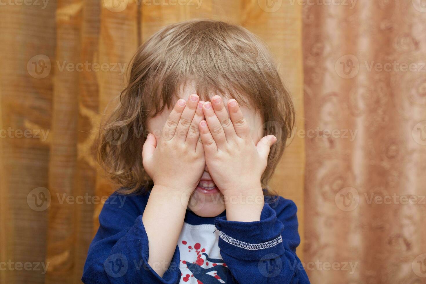 Child of 4 years old closed its face with palms. photo