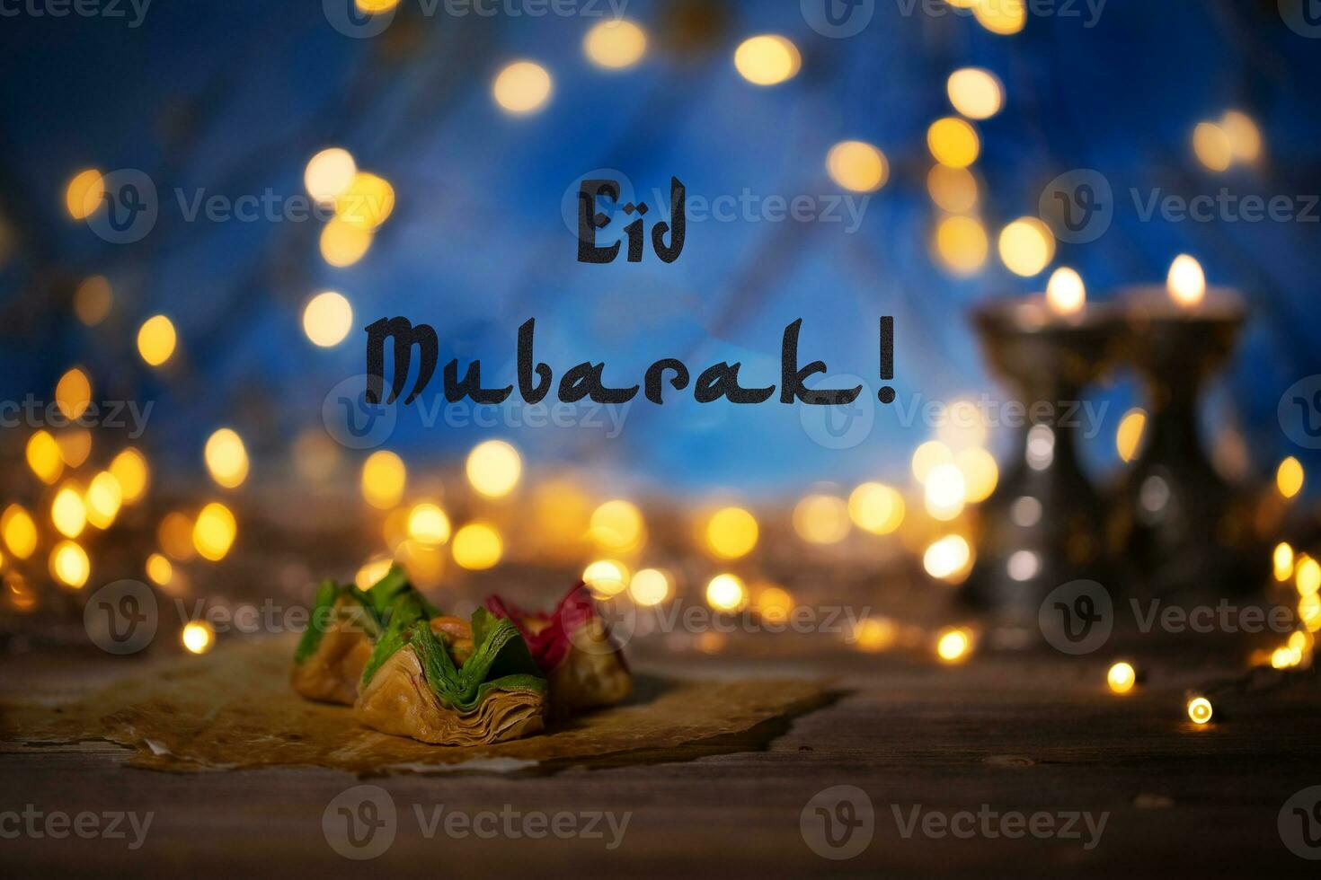 Congratulation Eid Mubarak Arabic sweets on a wooden surface. photo