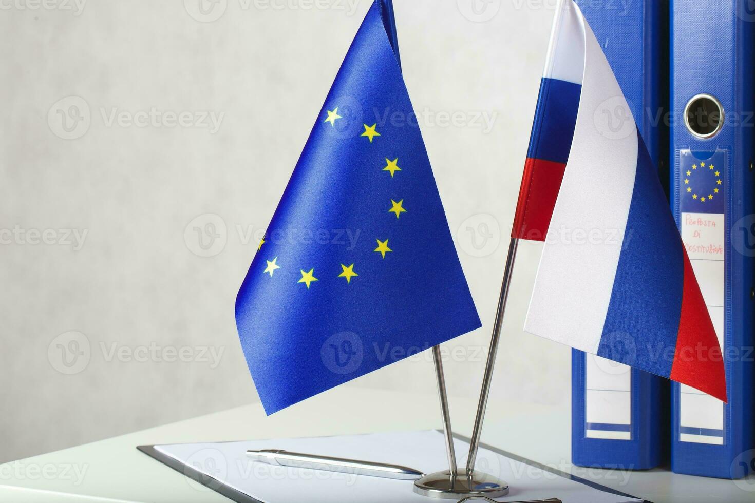 Two flags of the EU and Russia on a white table. Closeup photo