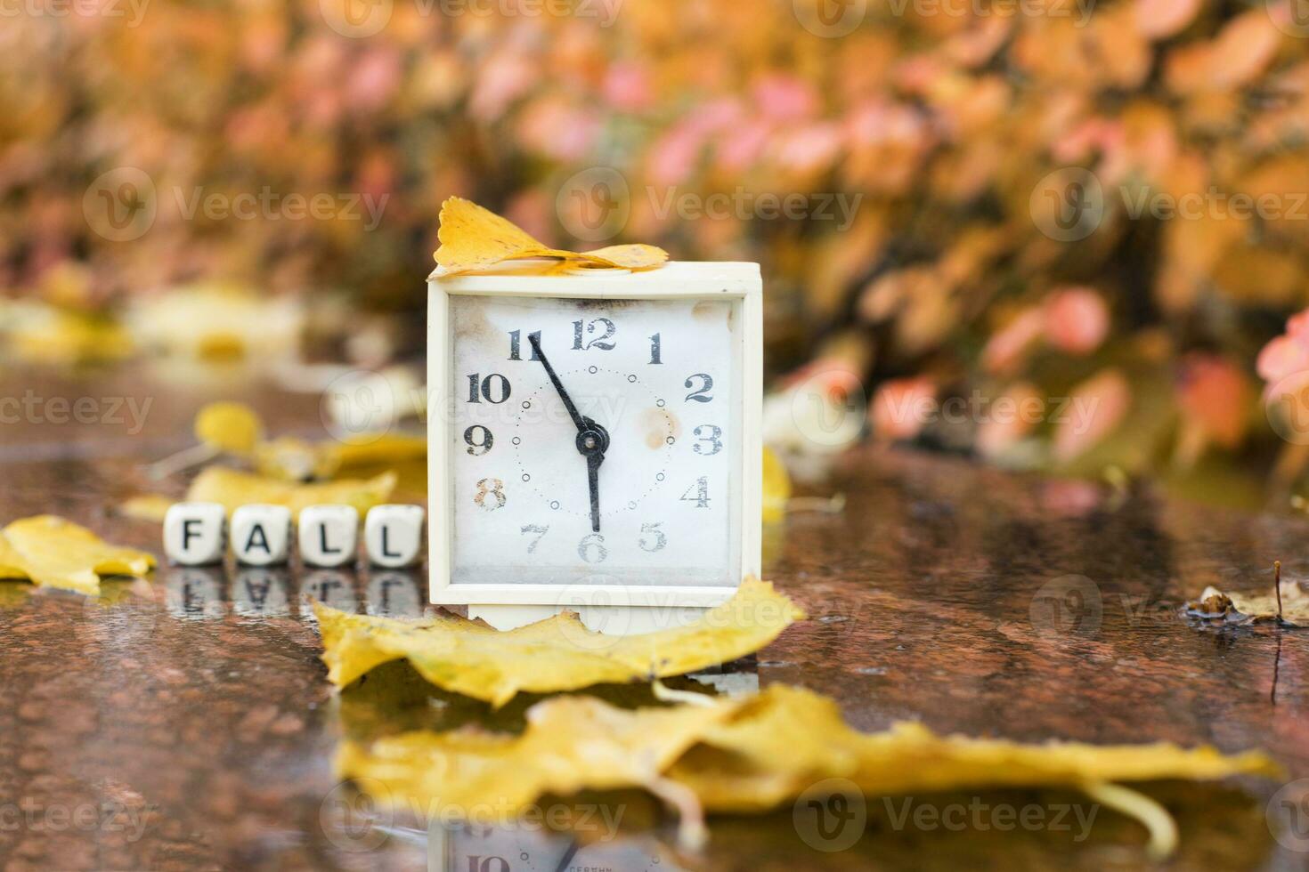 Old square alarm clock on a marble stone covered by rain. photo