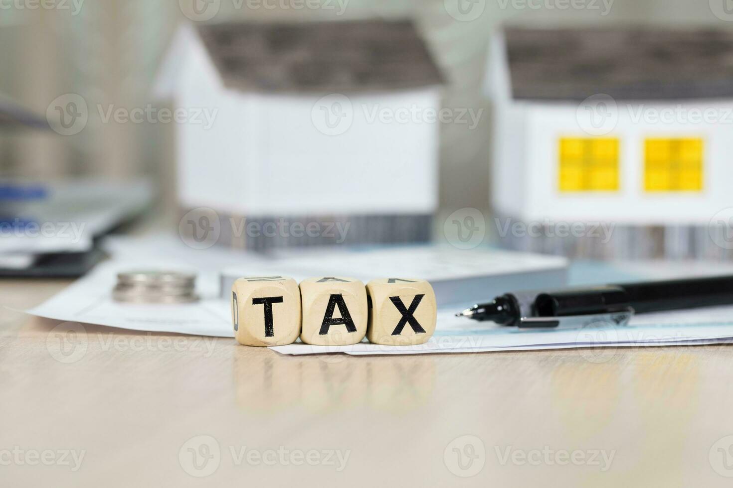 Word TAX composed of wooden letters in front of handmade house. photo