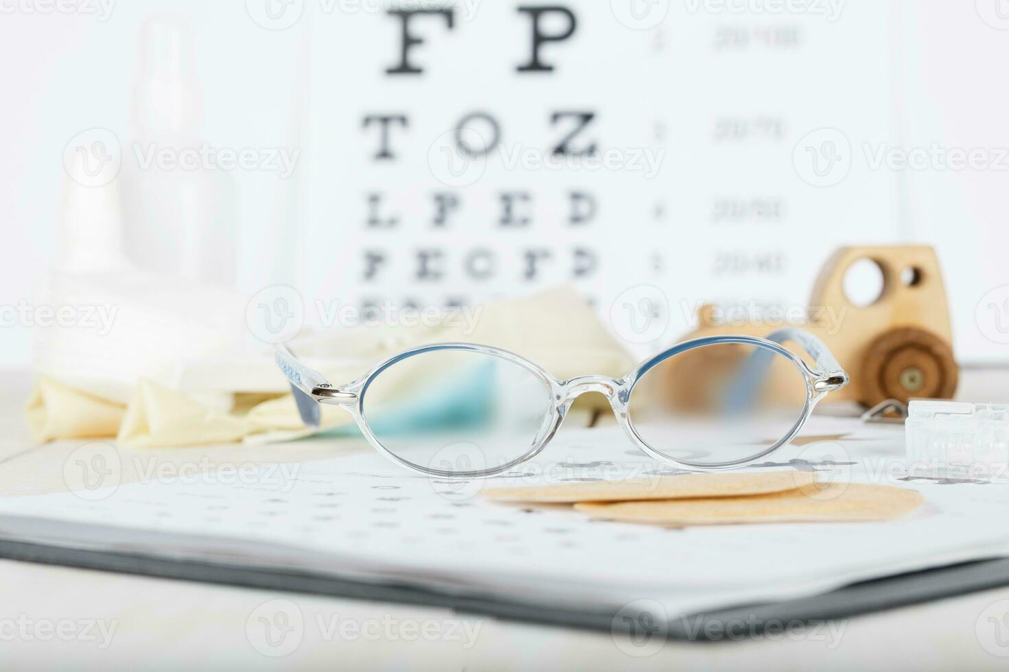 Eyeglasses for children on a eye chart close to eye pads. photo