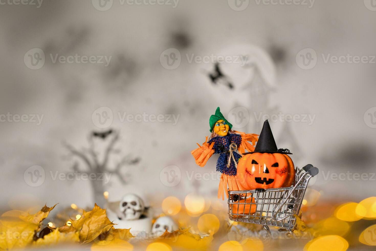 Witch and orange pumpkin in black hat in the small shopping cart. Closeup photo