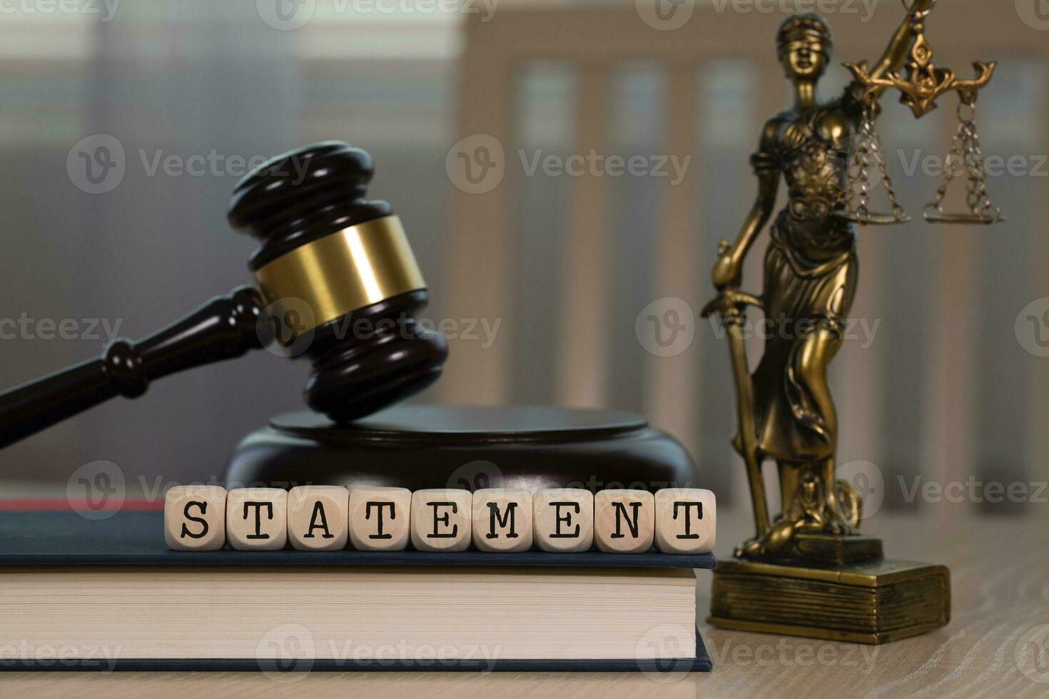 Word STATEMENT composed of wooden dices. Wooden gavel and statue of Themis in the background. photo