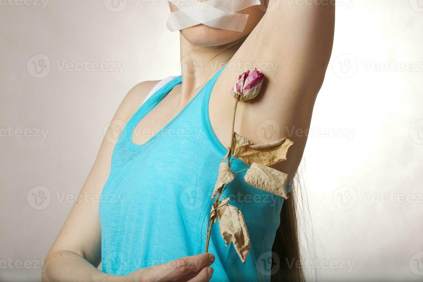 A young woman between keeps dehydrated rose close to her armpit. photo