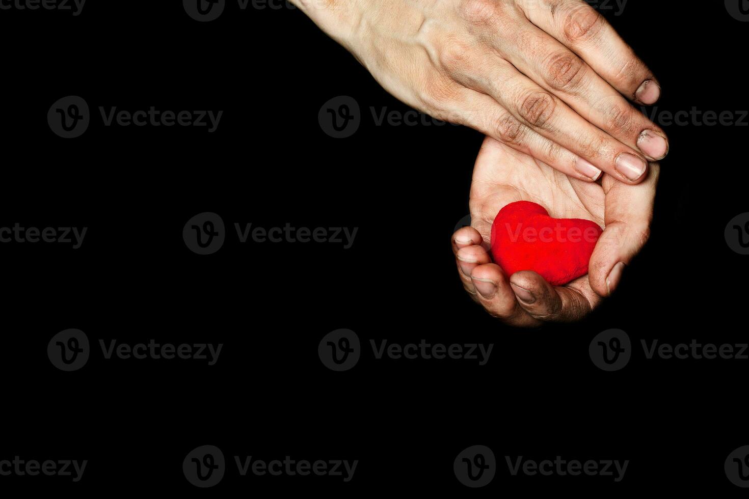 Palm of a peasant woman with plush red heart on a black fabric. photo