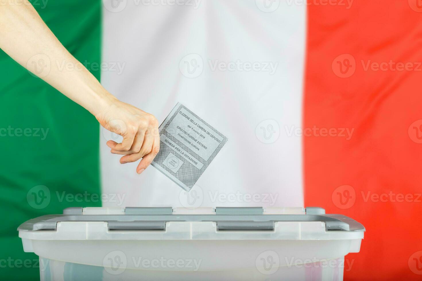 Female hand keeps ballot over ballot box. Italian flag in the background. photo
