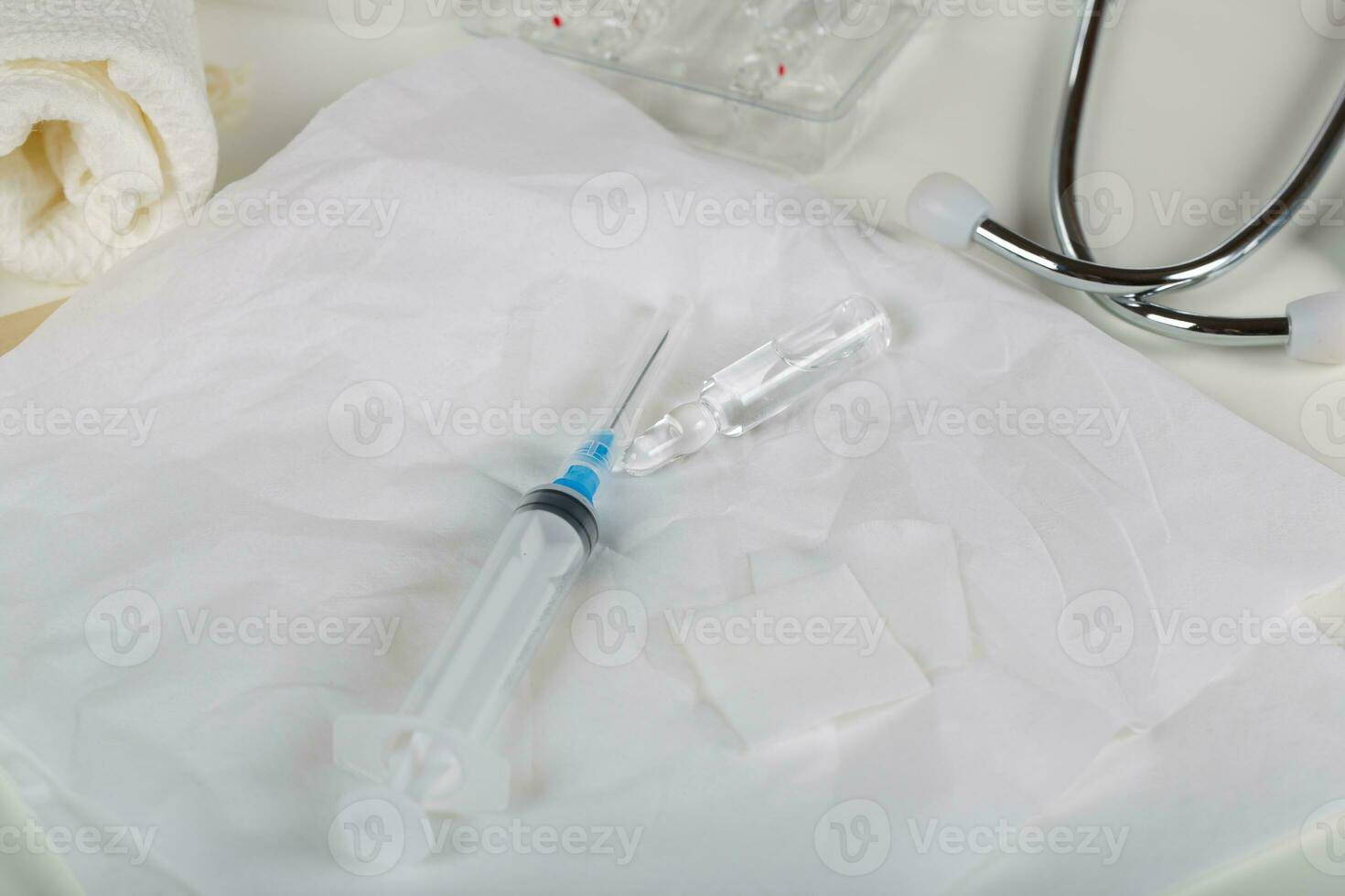 Syringe, alcohol wipe and glass ampule with antibiotics on a white napkin.Top view photo