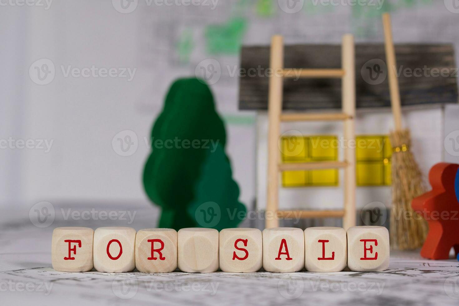 Words FOR SALE composed of wooden letter. Small paper house, wooden trees in the background. photo