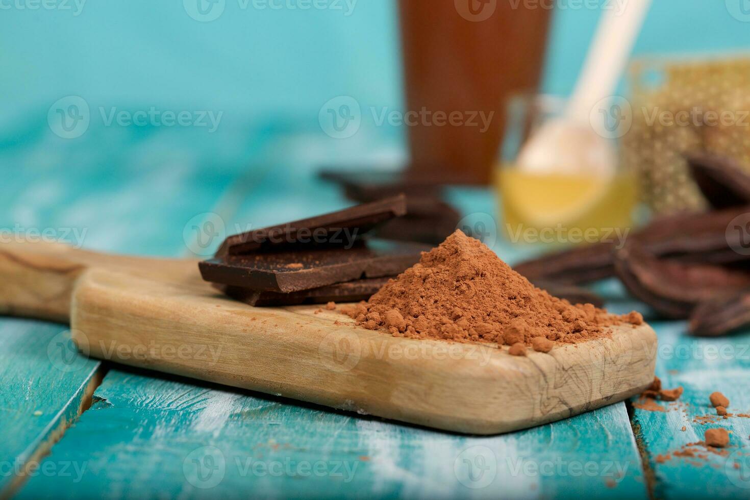 Carob pods and powder on a wooden surface. photo