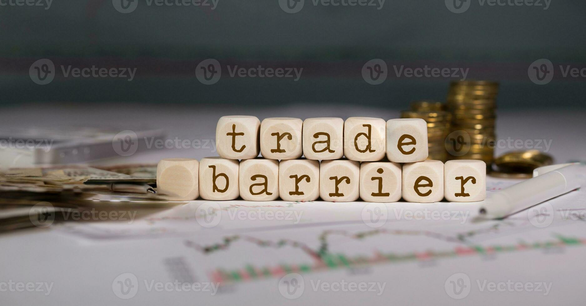 Words TRADE BARRIER composed of wooden letters. Stacks of coins in the background. photo